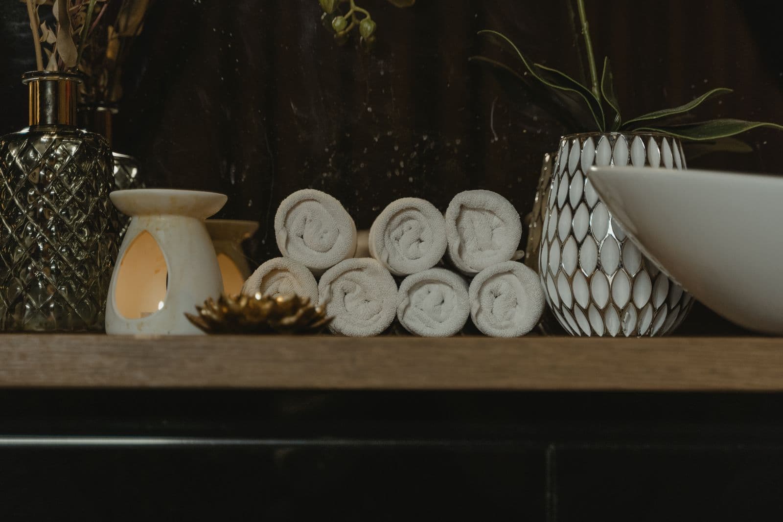 Rolled towels and a candle set out in a warm, calm spa space